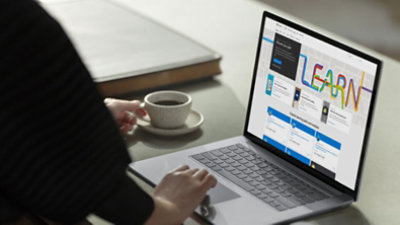A person exploring Microsoft Learn on laptop and drinking coffee