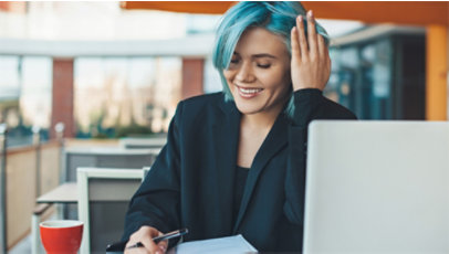 A woman with blue-colored hair working at her desk