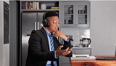 A man is sitting in kitchen and attending a call on his laptop 
