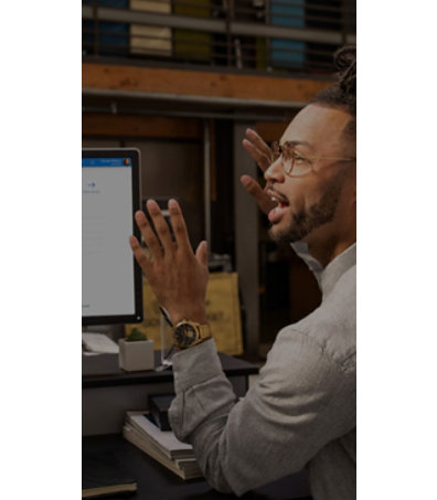 A man is sitting and talking in front of a desktop