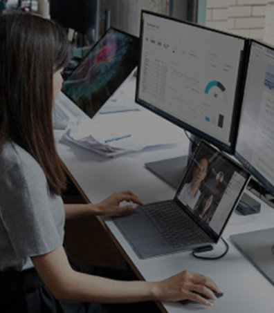 A woman working in front of two screens