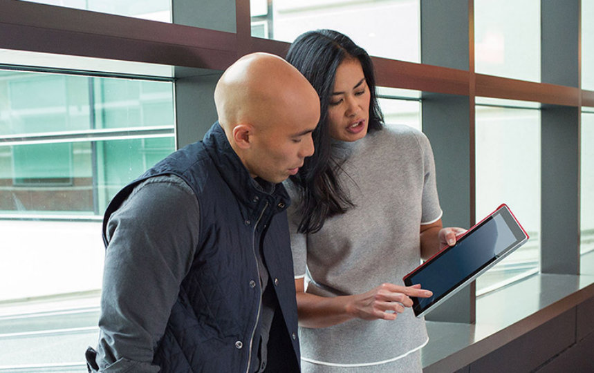 A woman showing her male office co-worker a tablet device in an office space