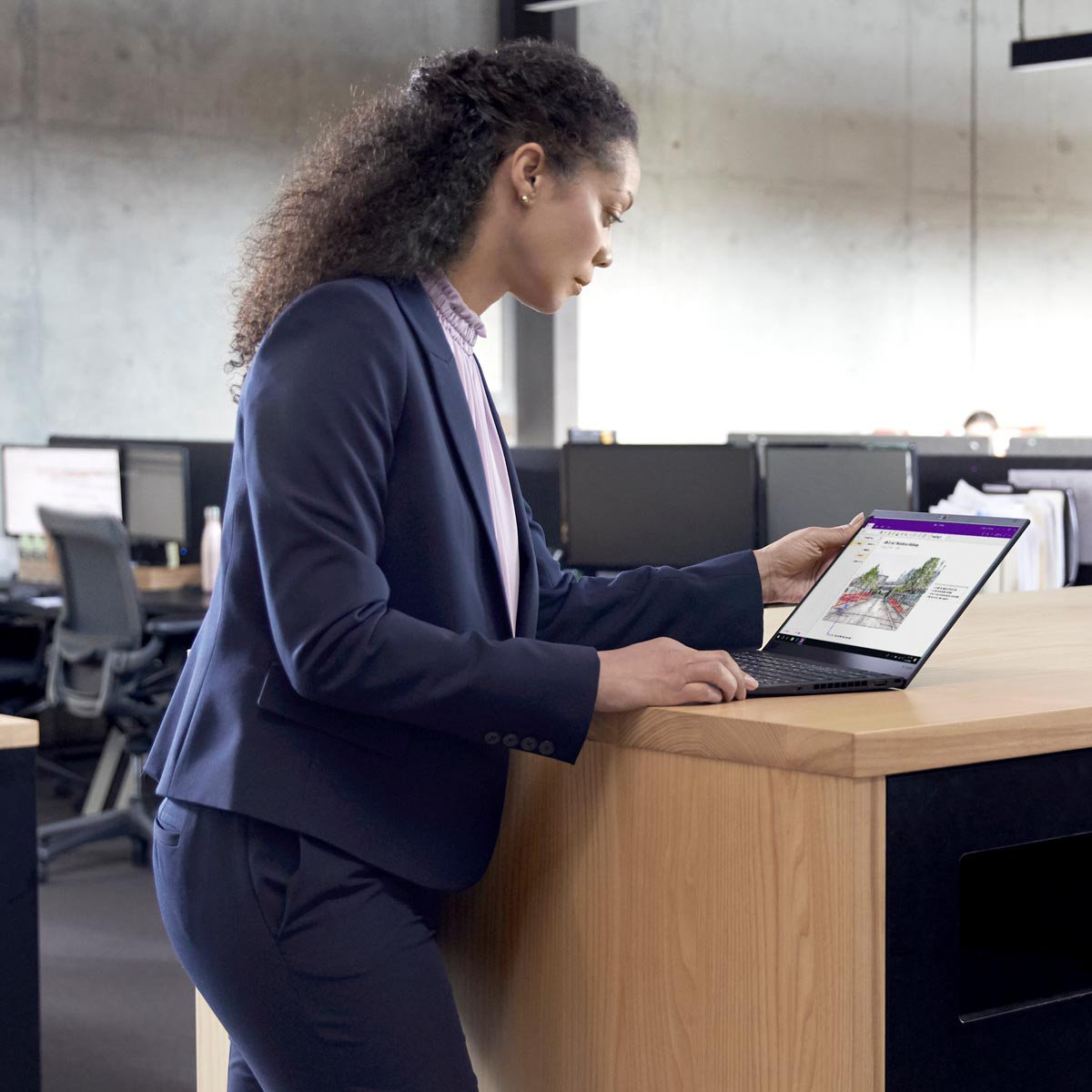 A female professional in office setting working on a standing desk
