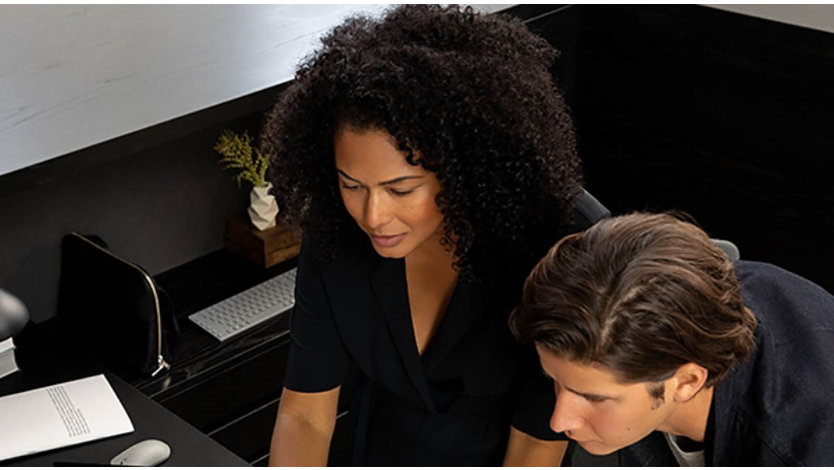 A male and female looking over their work on two tablet devices