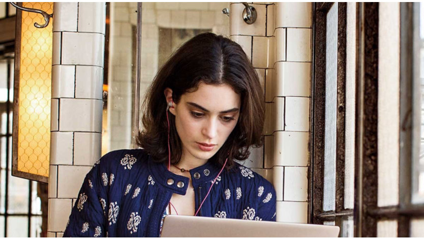A young woman looking at her laptop while walking