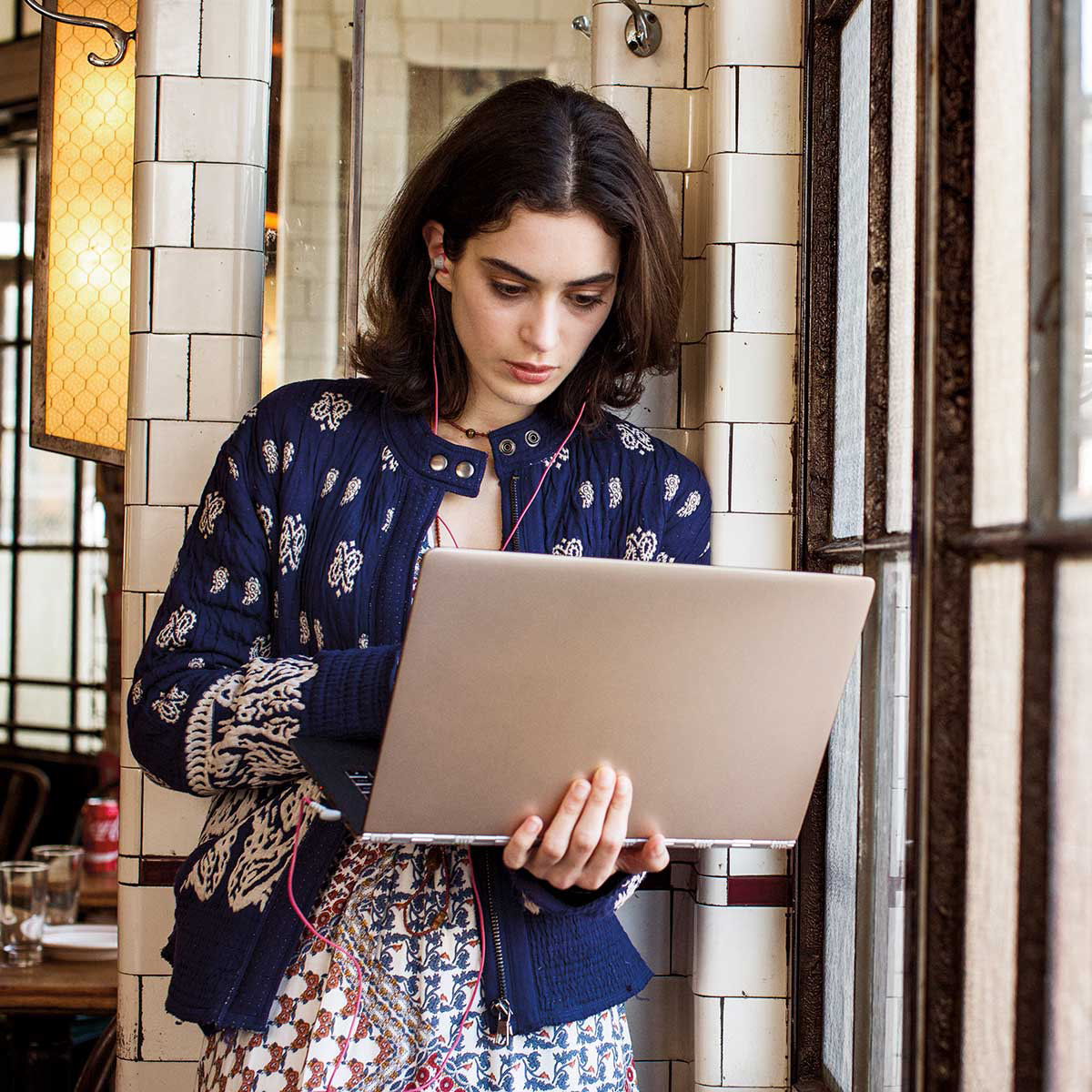 A young woman looking at her laptop while walking