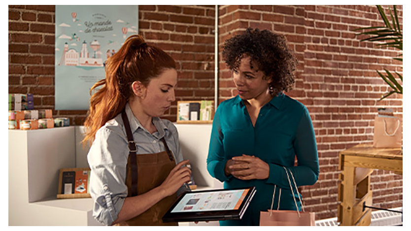 A photo of two women in a retail store. One is a sales assistant showing the customer something on a tablet