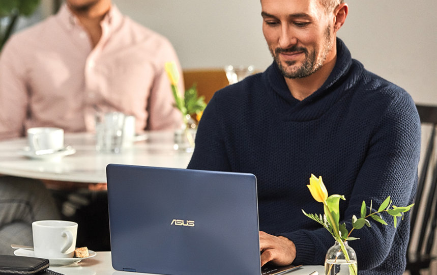 a close up of a man working on his laptop at a cafe