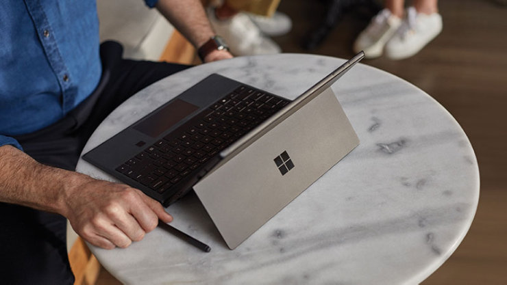 Un homme travaille sur une Surface Pro sur une table.