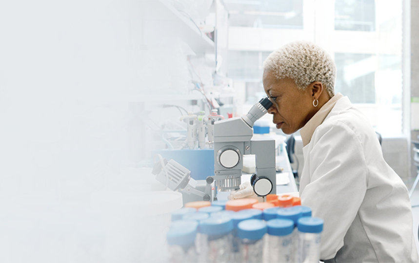 A woman in a research lab looking into a microscope