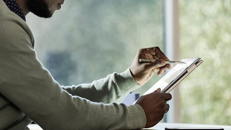 A male executive writing on his device using a Surface pen