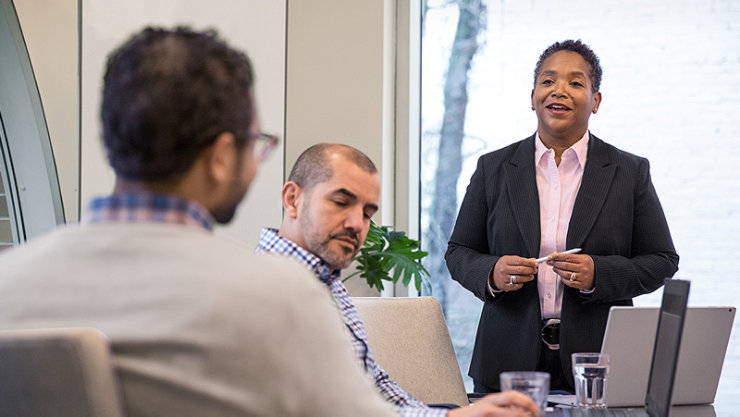 Une cadre en train de parler avec deux cadres dans une salle de conférence