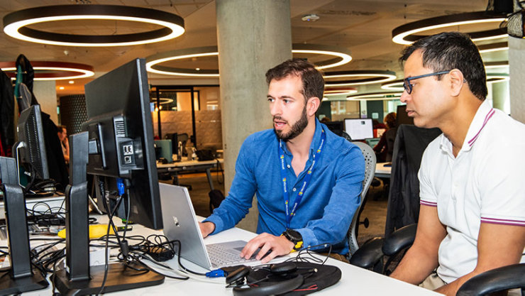 Un cadre masculin démontrant un détail de travail à l'écran à un autre cadre masculin