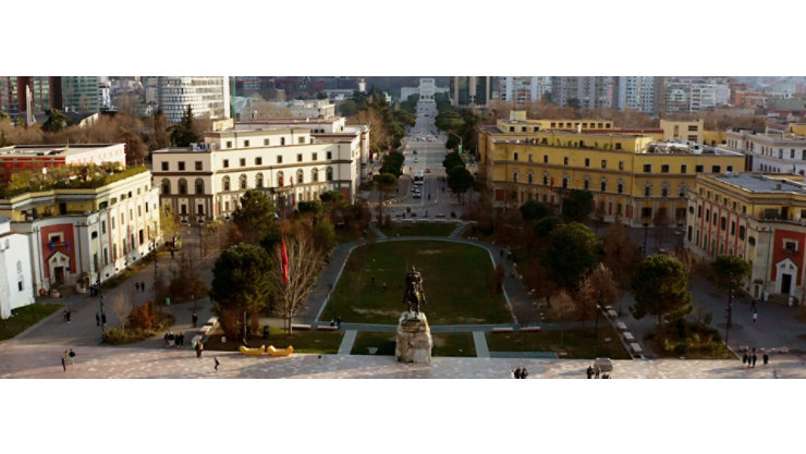 Aerial view of an Albaninan city center showcasing old buildings, a park, and a statue