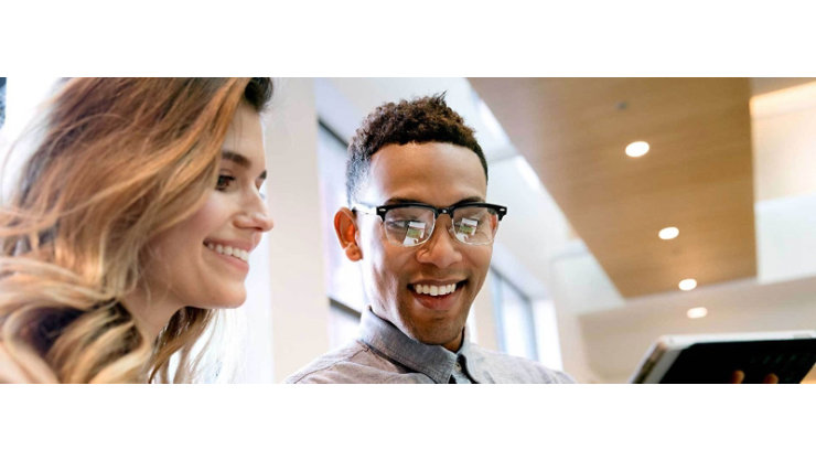 Two people smiling and looking at their screen