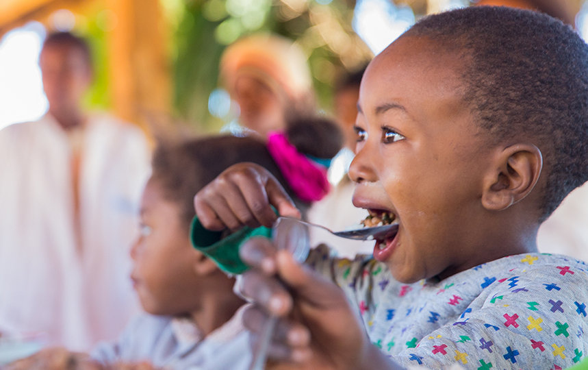 An African kid eating with spoon to mouth