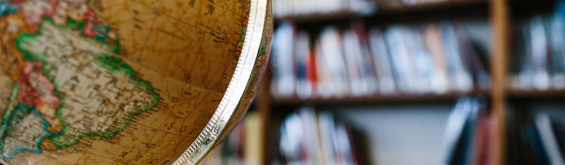 Color Photo of Library with tan globe as focal image and bookshelves in background