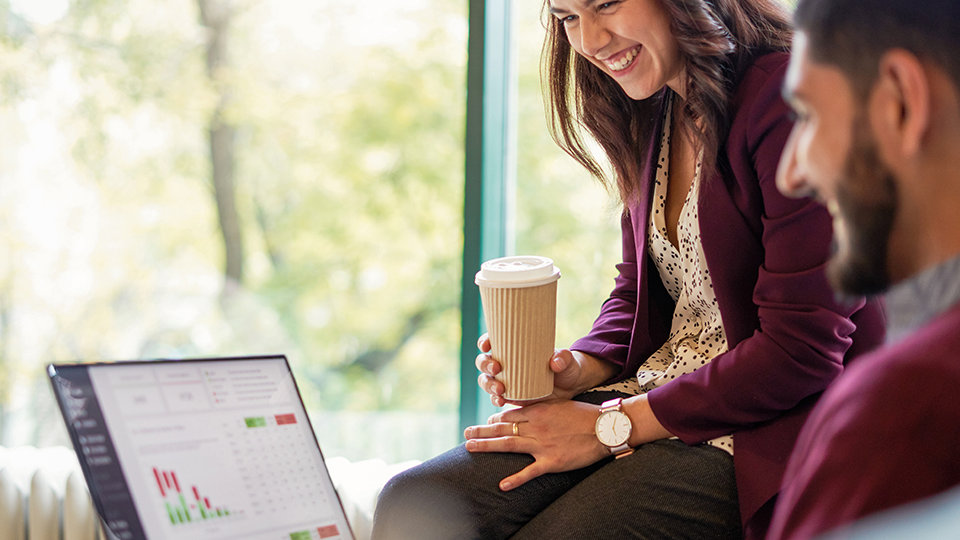 Two coworkers having informal meeting in modern office while looking at a data report on a computer screen