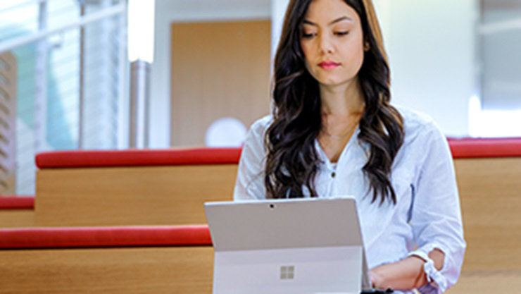 woman sitting on bench using a Surface device
