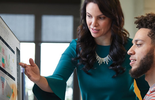 woman pointing to computer screen while man looks on