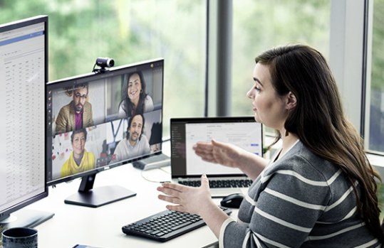 a woman sitting at a desk having a Teams meeting with colleagues