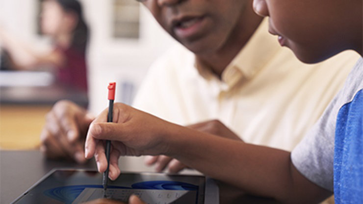 K-12 student at home, using Microsoft Teams on an Acer Spin Travelmate B3 for remote learning. A sibling is in the background, also engaged in remote learning on a Windows 10 device.