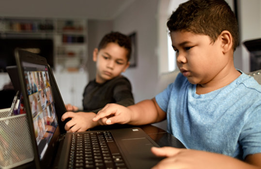 2 boys attending their class from laptop device.