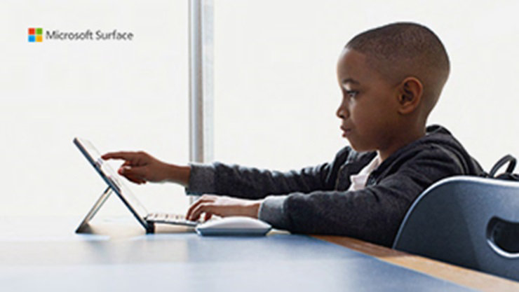 young boy sitting at a table using a device