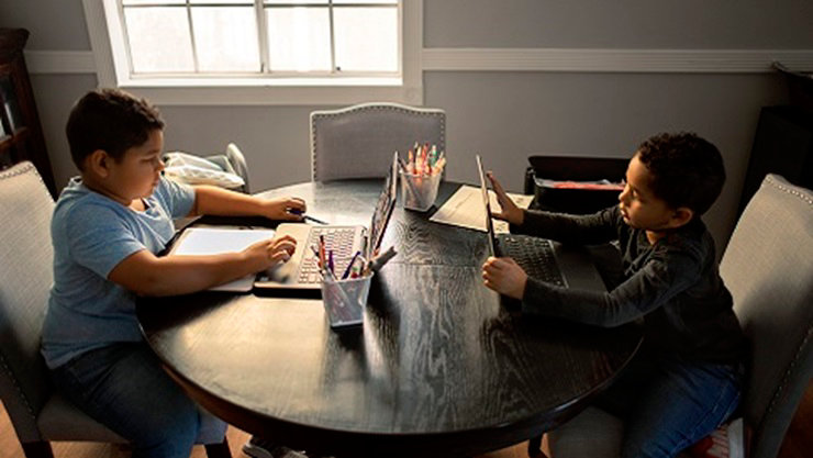 Two K-12 students sit together at a table using their devices