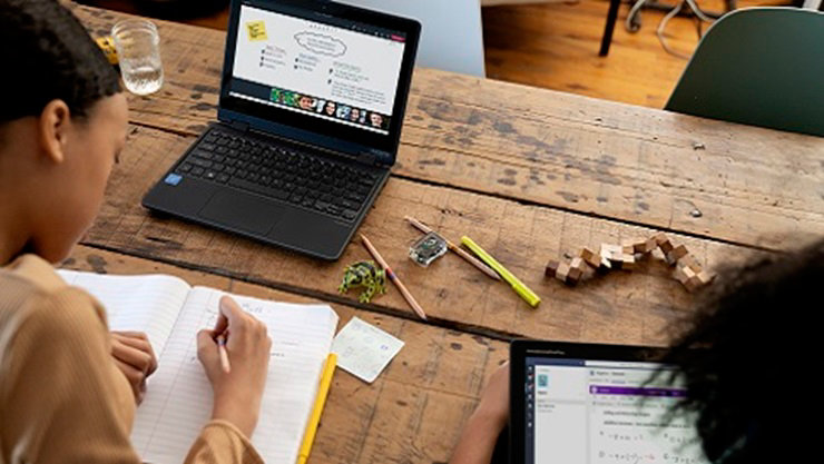 Two K-12 students sitting at a table working on school work