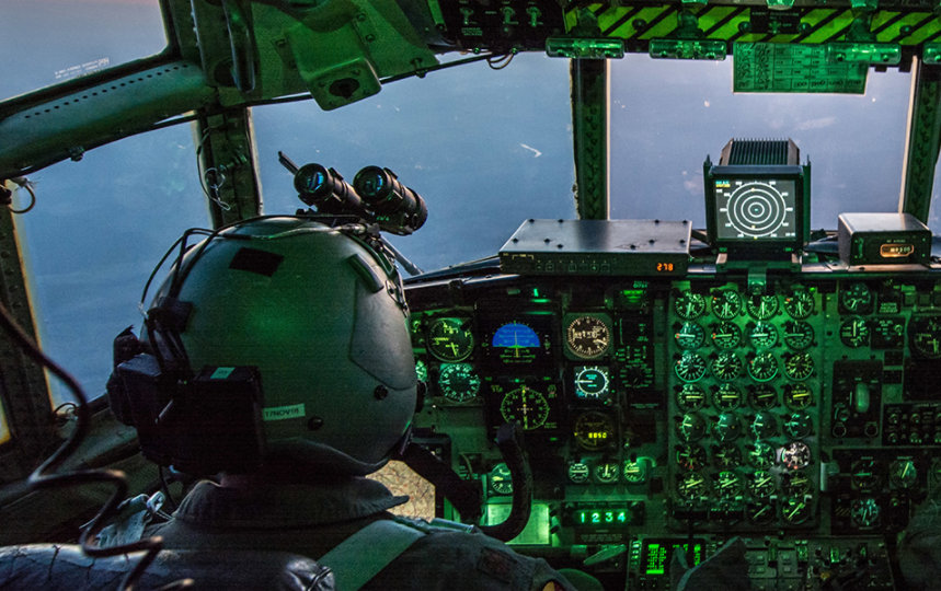 2 air force pilots in the cockpit of an aircraft flying at dusk