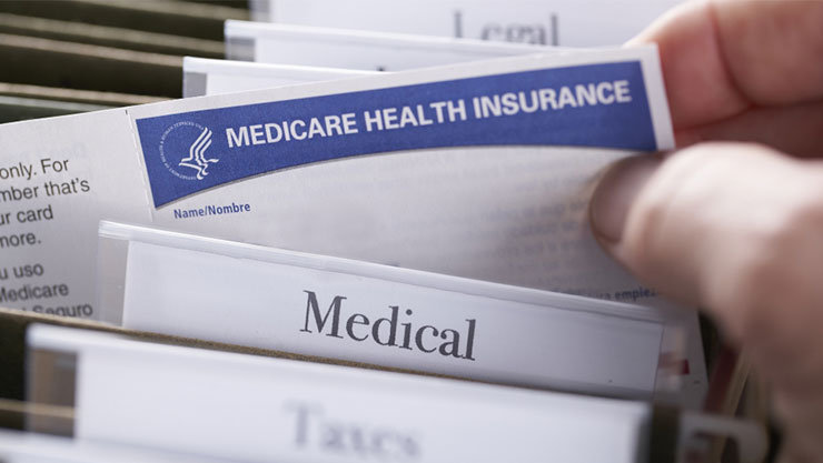 close-up photo of a hand pulling a sheet of paper out from a filing folder tabled ‘Medical’