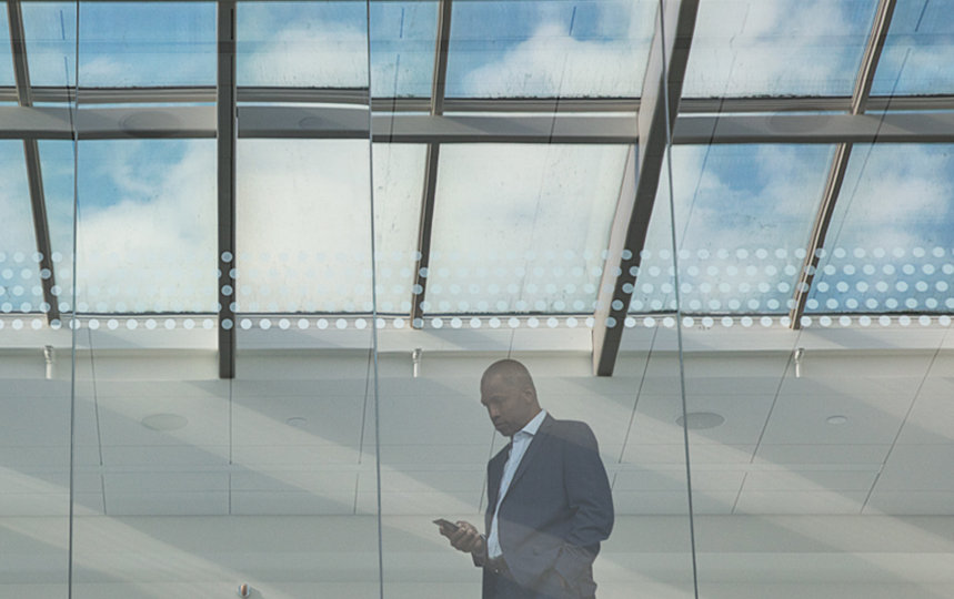 Businessman standing near the windows in a conference room, looking at phone