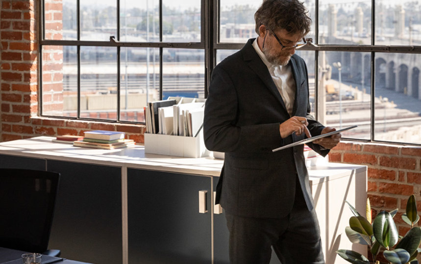 A man standing in his office and working on his tab