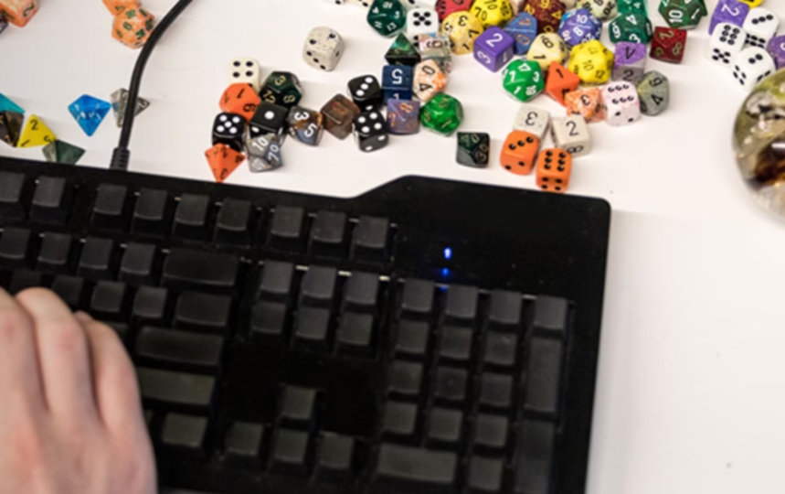 たくさんのサイコロが転がるテーブルの上でキーボードをタイプしている人。