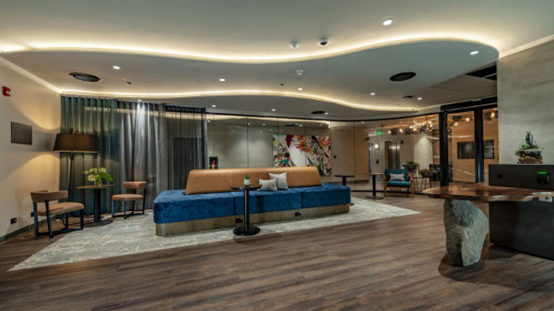 Una habitación grande con un sofá grande en el medio y una mesa pequeña con dos sillas en la esquina.