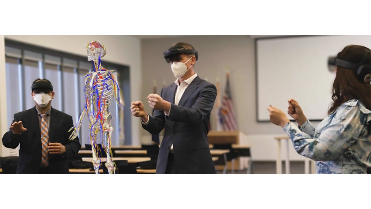 3 business professionals use mixed-reality headsets in a classroom to collaborate on a virtual reality skeleton