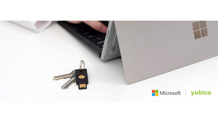 hands typing on a Microsoft table next to a YubiKey