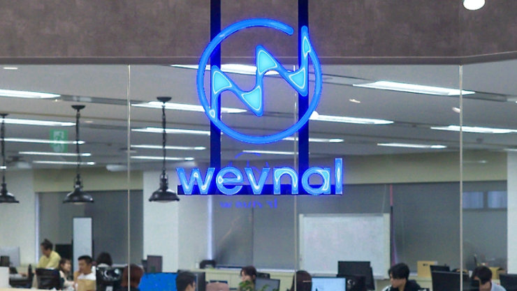 オープンな執務スペースを望むガラスの間仕切りに、青く光る「wevnal」のロゴ。