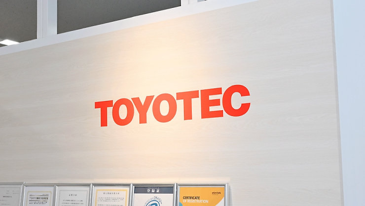 壁に掲げられた赤色のTOYOTECロゴと、その下に並ぶ各種認定証の額縁