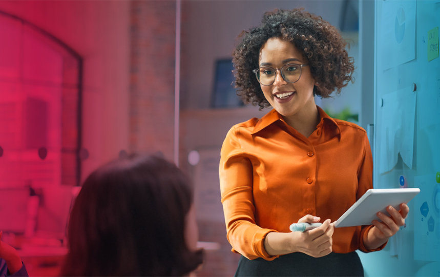 Une femme présente une tablette à un groupe de personnes, illustrant une discussion ou une démonstration.