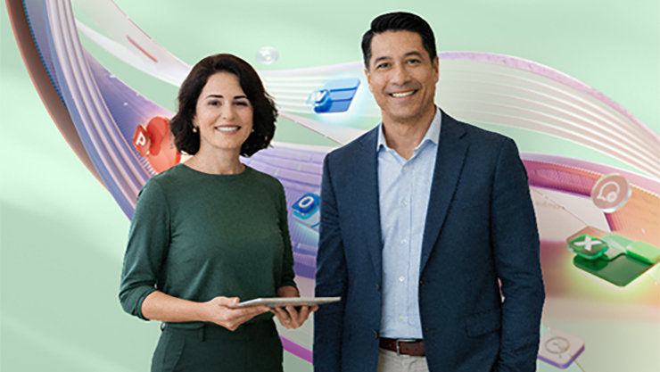 Une femme portant un haut vert et tenant une tablette, ainsi qu’un homme en costume bleu, se tiennent côte à côte en souriant.