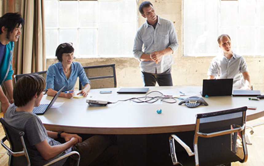 Plusieurs individus réunis autour d'une table dans un environnement de bureau, engagés dans une discussion productive.