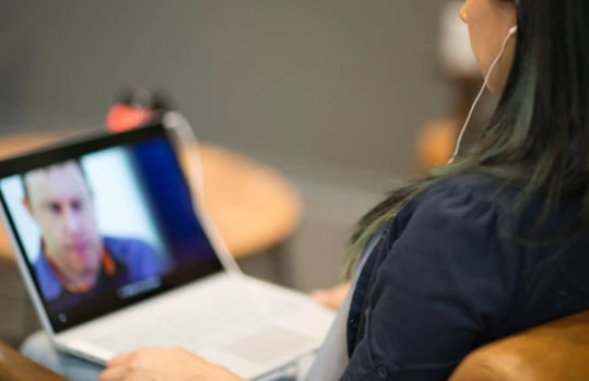 Eine Frau bedient einen Laptop, während sie Kopfhörer verwendet