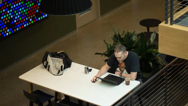 Ein Mann sitzt an einem Tisch und blickt auf einen Laptop
