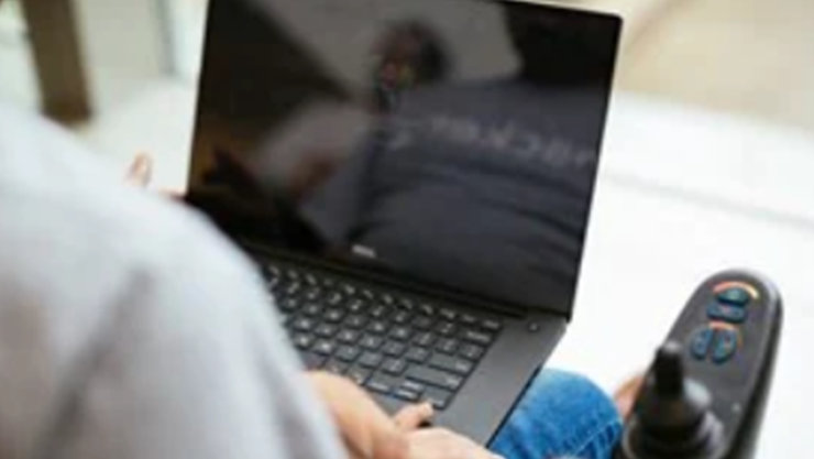 Die Kamera sieht einem Mann über die Schulter, der einen Laptop bedient