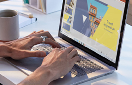 Zwei Hände bedienen einen Laptop auf einem weißen Schreibtisch