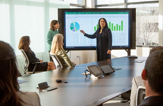 mulher apresentando resultados para um grupo de executivos em uma sala de reunião