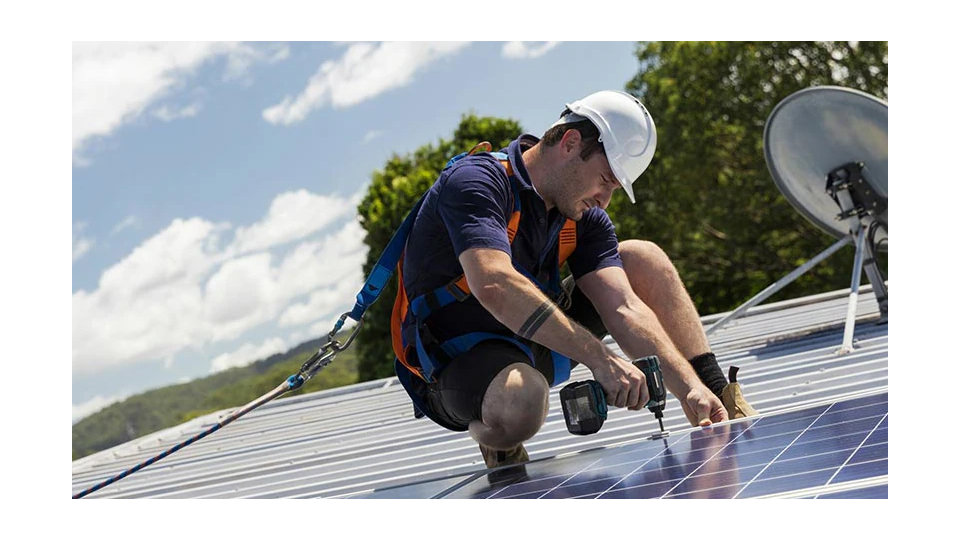 An electrician installing a solar panel on a roof