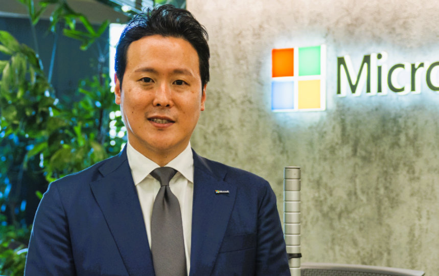オフィスに立つ翔太。背景にはマイクロソフトのロゴが見える。
